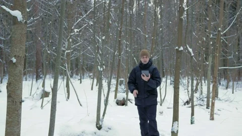 The young man goes in a winter forest in the snow and is oriented over the Stock Footage 71207153
