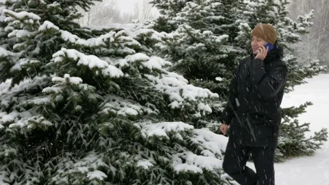 A young man goes on a winter forest and talking on the phone. Big snowfall. He Stock Footage 71213661