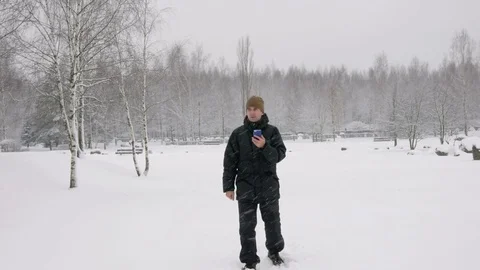 The young man goes in a winter forest in the snow and is oriented over the phone Stock Footage 71216832