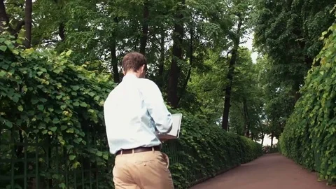 Young man going at park using laptop receiving good news and celebrating success Video stock 77168985