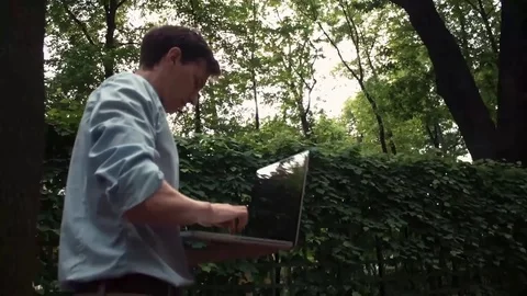 Young man going at park using laptop receiving good news and celebrating success Stock Footage 77168995