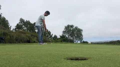 Young man on golf green making a long put, hole in one, celebrating and cheering Stock Footage 118659570