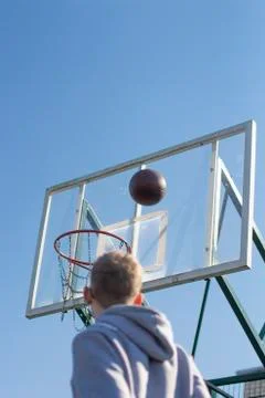 A young man in a gray jacket playing basketball 스톡 사진