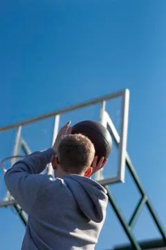 A young man in a gray jacket playing basketball Stock Photos