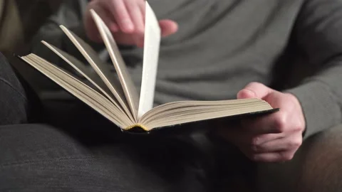 Young man in gray sweater reading a book. Stock Footage 236000840