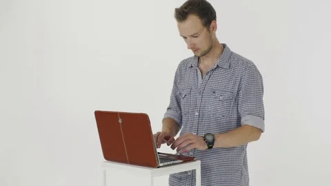 Young man in a grey shirt nervously typing  on a laptop and closing it 스톡 동영상 80357346