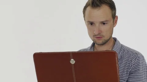 A young man  in a grey shirt  working on a laptop, surprises and smiles. 스톡 동영상 80356689