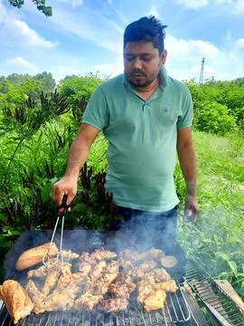 Young man grilling chicken stack on heating. Chicken stack barbecue on heating Fotos Stock