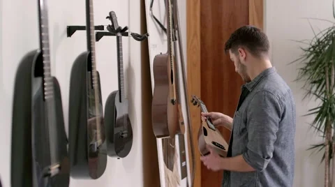 Young man in guitar store Stock Footage 64888648
