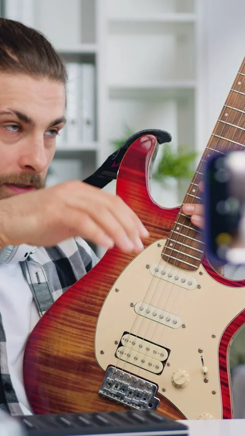 Young man guitar teacher talking to camera and showing how play, blogger man cre Stock Footage 333186509