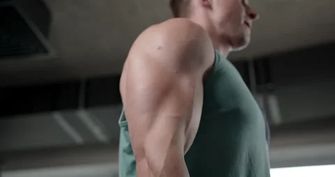 A young man in the gym does a biceps exercise while lifting a barbell  Stock Footage 158916786