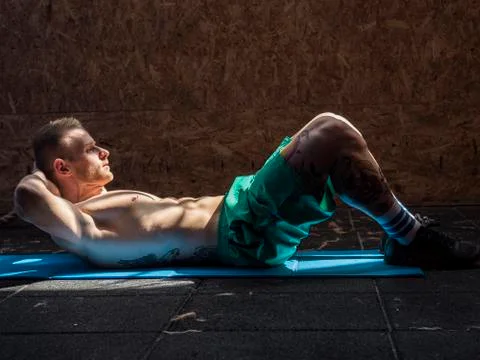 Young man in gym doing exercises for abs. Stock Photos