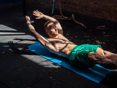 Young man in gym doing exercises for abs. Stock Photos