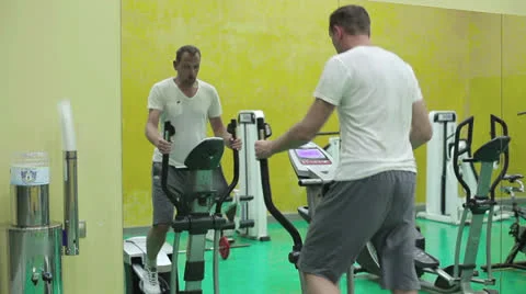 Young man at the gym exercising on the xtrainer machines Stock Footage 24951173