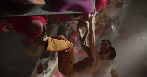 Young man with gym trainer climbing wall Stock Footage 259986143