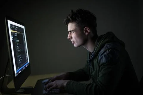 Young man hacking server in dark room. Young man programm code on pc in dark  Foto stock