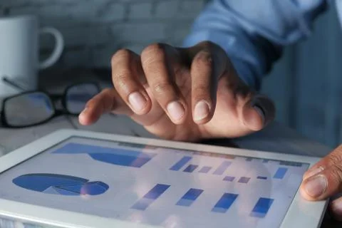 Young man hand analyzing financial data and chart on digital tablet Foto stock