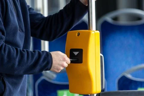 Young man hand inserts the bus ticket into the validator, validating and ticking Фото