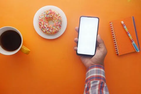 Young man hand using smart phone with tea and cookies on table Stock Photos