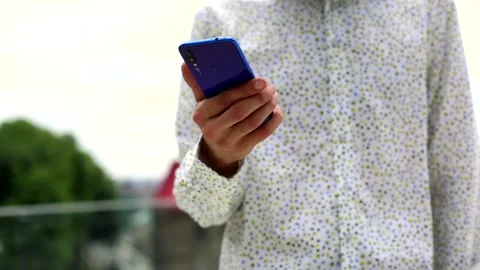 Young man hand using smartphone standing outdoor in white elegant shirt. Stylish Stockbeeldmateriaal 135373438