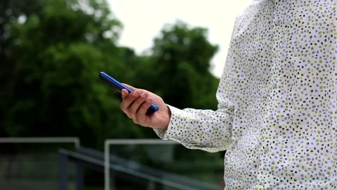 Young man hand using smartphone standing outdoor in white elegant shirt. Stylish Stockbeeldmateriaal 135373483