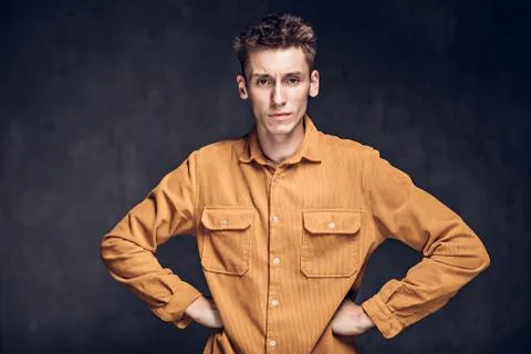 Young man with hands on hips on dark background Stock Photos