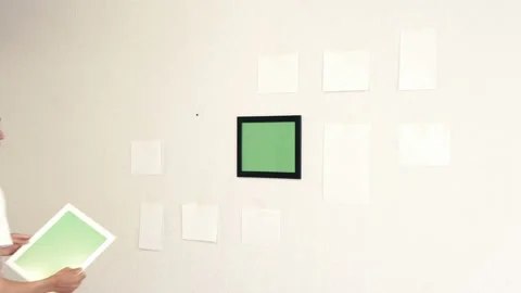 Young man hangs a white photo frame on a wall Stock Footage 111832145