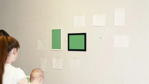 Young man hangs a white photo frame on a wall Stock Footage 111833024