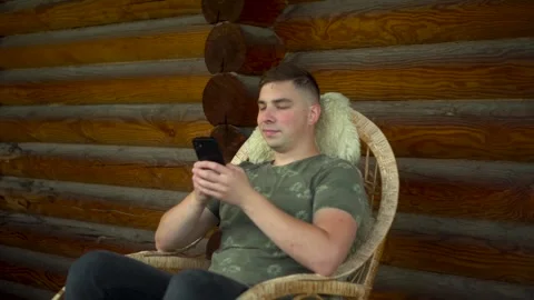 A young man is happily engaged with his smartphone while sitting comfortably in Stock-Footage 284937460