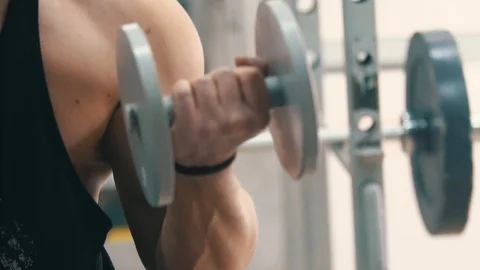 Young man hard training biceps muscles in gym Stock Footage 87269427