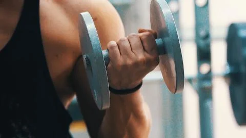 Young man hard training biceps muscles in gym Stock Photos