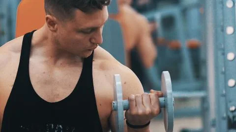 Young man hard training biceps muscles in gym Stock Photos