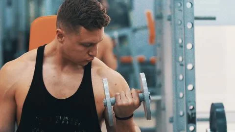 Young man hard training biceps muscles in gym Stock Photos
