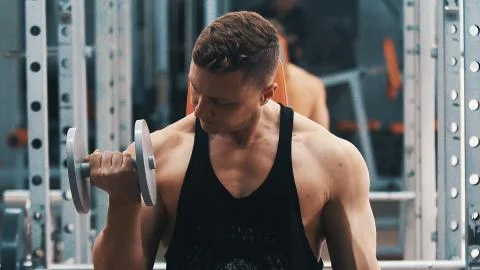Young man hard training biceps muscles in gym Stock Photos