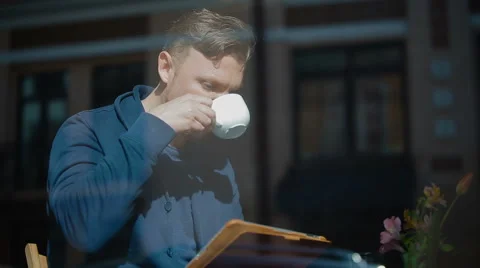 The young man has coffee and reads news in the tablet Video stock 62549594