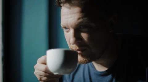 The young man has coffee and looks out of the window. Stock Footage 62549666