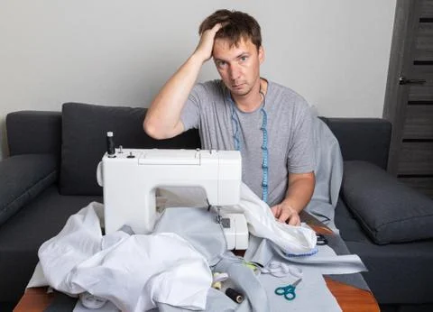 The young man has difficulty learning a new skill. Difficult work on a sewing Stock Photos