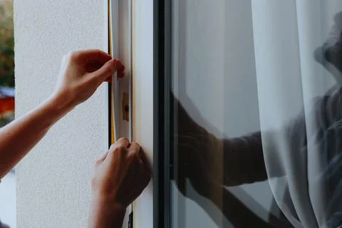 A young man has his window frame insulated. Stock Photos