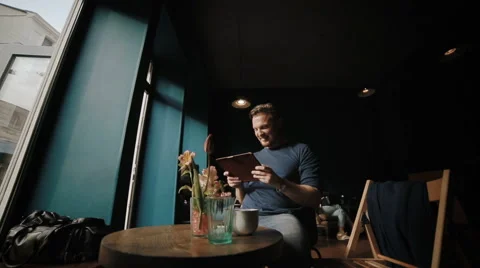 The young man has a rest in cafeteria and reads news Video stock 62549710