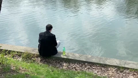 A young man has time to think about something important on the river bank. Stock Footage 239018173