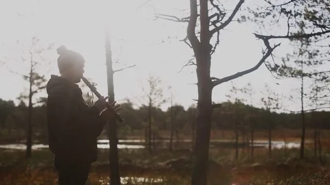Young man in the hat playing native american flute in the nature at sunrise Stock Footage 80340225