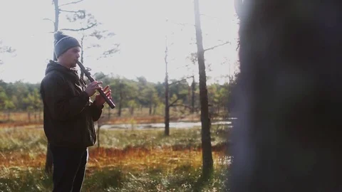 Young man in the hat playing native american flute in the nature at sunrise Stock Footage 80340296