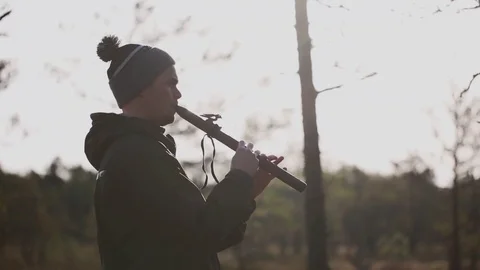 Young man in the hat playing native american flute in the nature at sunrise Stock Footage 80340331