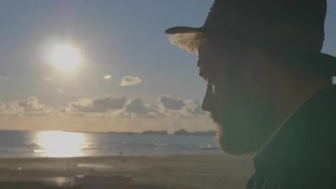 Young man with hat at sunset covering sun looking horizon 스톡 동영상 332418789