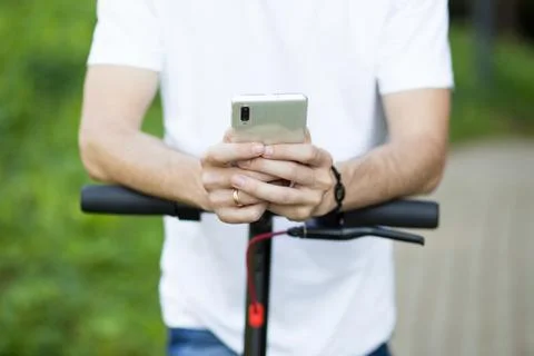 Young man in hat use mobile phone, book online rental electric scooter Stock Photos