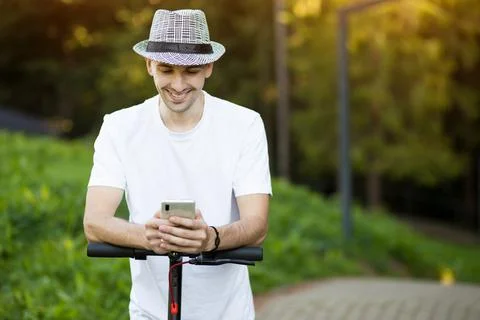 Young man in hat use mobile phone, book online rental electric scooter Stock Photos