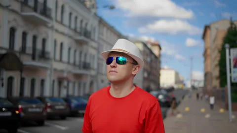 A young man in a hat walks around the city examines the buildings around Stock Footage 135827133