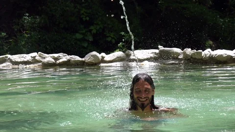 Young man havig a shower in splasing water jet in a hot springs in the Caribbean Stock Footage 91195613