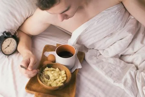 Young man having Breakfast in bed in the morning. Stock Photos