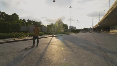 Young man having call and talking to headphones while standing on skateboard Stock Footage 99957464